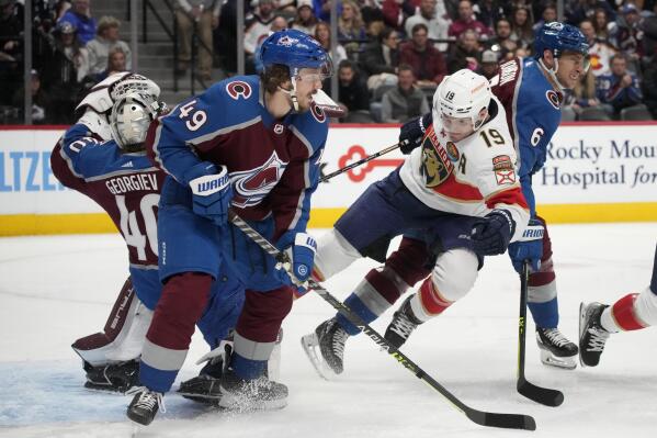 Florida Panthers left wing Matthew Tkachuk, front center, tumbles to the ice while driving between Colorado Avalanche defenseman Samuel Girard, front left, and defenseman Erik Johnson to put the puck on goaltender Alexandar Georgiev, back, in the second period of an NHL hockey game Tuesday, Jan. 10, 2023, in Denver. (AP Photo/David Zalubowski)