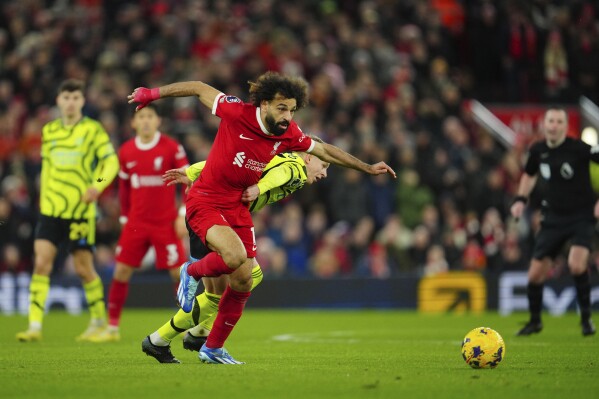 Liverpool's Mohamed Salah, left, and Arsenal's Oleksandr Zinchenko fight for the ball during the English Premier League soccer match between Liverpool and Arsenal at Anfield stadium in Liverpool, England, Saturday, Dec. 23, 2023. (AP Photo/Jon Super)