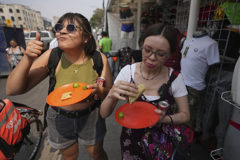 A customer gives a thumbs up while eating a taco from taco stand Tacos El Califa de León, in Mexico City, Wednesday, May 15, 2024. Tacos El Califa de León is the first ever taco stand to receive a Michelin star from France's food guide.  (AP Photo/Fernando Llano)