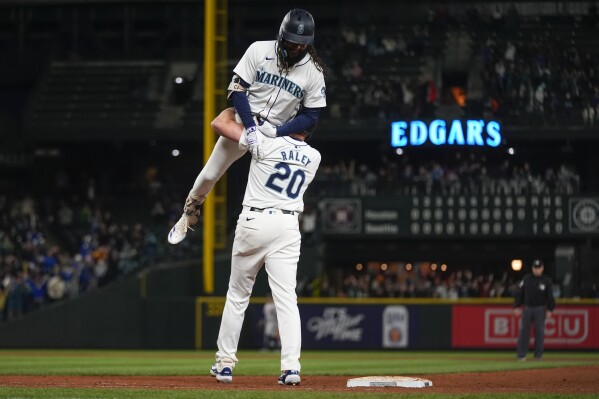 Seattle Mariners' J.P. Crawford is lifted by Luke Raley (20) after driving in the winning run with sacrifice fly against the Houston Astros during the 10th inning of a baseball game Wednesday, May 29, 2024, in Seattle. The Mariners won 2-1. (AP Photo/Lindsey Wasson)