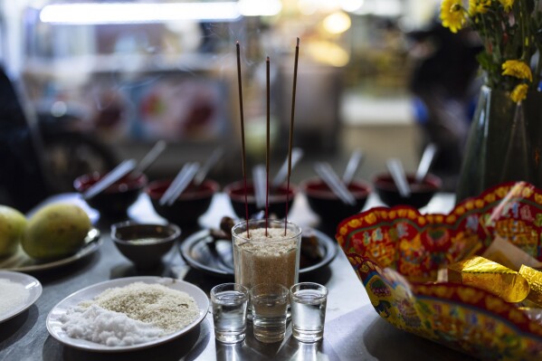 Incense, placed in a cup of rice, burns on an altar outside a restaurant to seek prosperity in Ho Chi Minh City, Vietnam, Saturday, Jan. 27, 2024. Rice isn't just the mainstay of most meals, it is considered a gift from the gods and continues to be venerated. (AP Photo/Jae C. Hong)