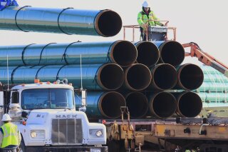 FILE - In this May 9, 2015, file photo, workers unload pipes in Worthing, S.D., for the Dakota Access oil pipeline that stretches from the Bakken oil fields in North Dakota to Illinois. A federal appeals court on Tuesday, Jan. 26, 2021, upheld the ruling of a district judge who ordered a full environmental impact review of the Dakota Access pipeline in North Dakota. Following a complaint by the Standing Rock Sioux Tribe, U.S. District Judge James Boasberg said in April 2020 that a more extensive review was necessary than the one already conducted by the U.S. Army Corps of Engineers.  (AP Photo/Nati Harnik, File)