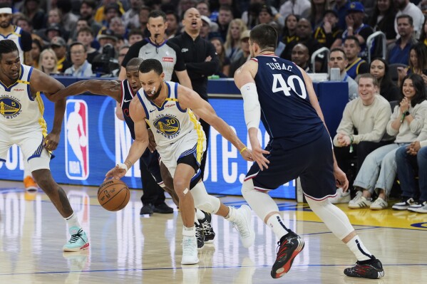Golden State Warriors guard Stephen Curry (30) moves the ball while defended by Los Angeles Clippers guard Kris Dunn, second from left, during the first half of an NBA basketball game Sunday, April 13, 2025, in San Francisco. (AP Photo/Godofredo A. Vásquez)
