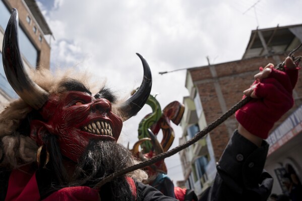 Wearing a devil mask, a reveler dances through the streets during the 