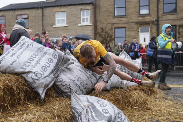 A contestant drops his bag after racing a 1.1 km course with a 50kg sack of coal during the World Coal Carrying Championships in Ossett, West Yorkshire, England, Monday, April 21, 2025. (AP Photo/Jon Super)