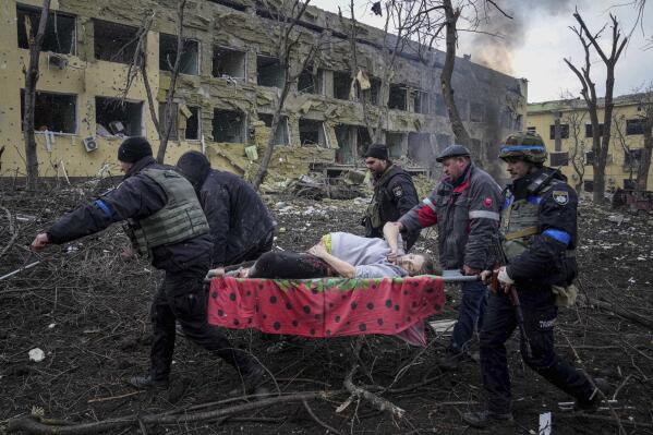 FILE - Ukrainian emergency workers and volunteers carry an injured pregnant woman outside a damaged maternity hospital in Mariupol, Ukraine, Wednesday, March 9, 2022. A Russian attack has severely damaged a maternity hospital in the besieged port city of Mariupol, Ukrainian officials say. (AP Photo/Evgeniy Maloletka, File)
