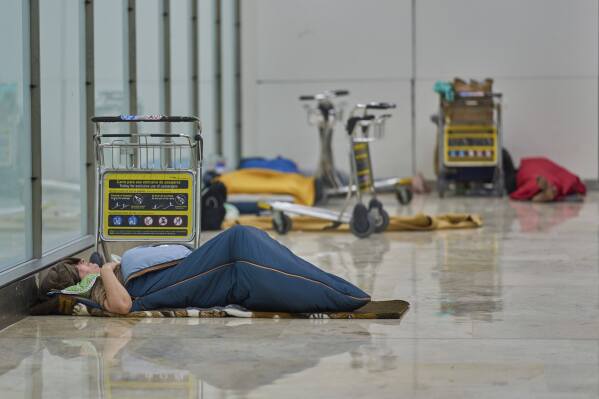 People sleep on the floor of Terminal 4 at Adolfo Suarez-Madrid Barajas Airport in Madrid, Spain, Thursday, May 15, 2025. (AP Photo/Manu Fernandez)