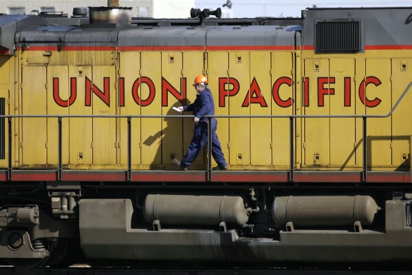 FILE - A maintenance worker walks past the company logo on the side of a locomotive in the Union Pacific Railroad fueling yard in north Denver, Oct. 18, 2006. Union Pacific announced Wednesday, Nov. 1, 2023, that it is trimming the ranks of the railroad's management employees as part of the new CEO's push to eliminate layers of bosses involved in decisions. (AP Photo/David Zalubowski, File)