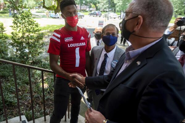 FILE - in this Aug. 19, 2021, file photo, Louisiana quarterback Levi Lewis greets Gov. John Bel Edwards as he tours the University of Louisiana Campus vaccination site as part of the university's Shot for $100 campaign in Lafayette, La. Several months since COVID-19 vaccinations were made widely available in the U.S., the subject continues to disrupt  professional and college sports. (Scott Clause/The Daily Advertiser via AP, File)