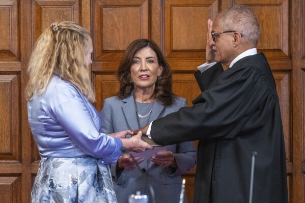 In this image provided by the Office of the Governor of New York, Rowan Wilson, right, recites a celebratory oath administered by Gov. Kathy Hochul as he sworn in as the first Black chief judge of the state’s highest court, the New York Court of Appeals, Tuesday, Sept. 12, 2023, in Albany, N.Y. Wilson's wife Grace Wilson, left, holds the Bible during the ceremony. Wilson, who was officially sworn in immediately after his confirmation by the Legislature last April, had has been exercising the full powers of the post, but Tuesday's ceremony was intended to bring more pomp to a landmark moment.(Office of Governor of New York/Darren McGee via AP)