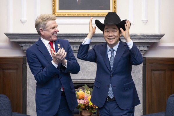 In this photo released by the Taiwan Presidential Office, Taiwan President Lai Ching-te, right, puts on a cowboy hat given by Rep. Michael McCaul, R-Texas during a meeting in Taipei, Taiwan, Monday, May 27, 2024. A U.S. congressional delegation met Taiwan's new leader on Monday in a show of support shortly after China held drills around the self-governing island in response to his inauguration speech. (Taiwan Presidential Office via AP)