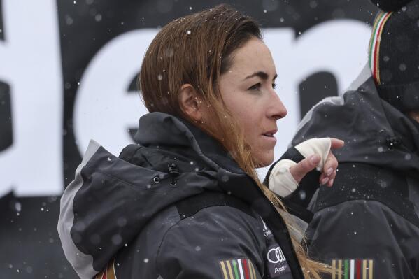 Italy's Sofia Goggia, her left hand wrapped in a bandage, stands in the finish area after completing an alpine ski, women's World Cup downhill race, in St. Moritz, Switzerland, Friday, Dec.16, 2022. (AP Photo/Marco Trovati)