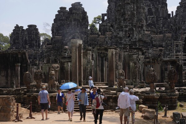 Tourists visit Bayon temple at Angkor Wat temple complex in Siem Reap province, Cambodia, Wednesday, April 3, 2024. The Angkor site is one of the largest archaeological sites in the world, spread across some 400 square kilometers (155 square miles) in northwestern Cambodia. It contains the ruins of Khmer Empire capitals from the 9th to 15th centuries, including the temple of Angkor Wat, featured on several Cambodian banknotes, such as the 2,000 riel note depicting rice farmers working fields around the temple, as well as the country's flag. (AP Photo/Heng Sinith)