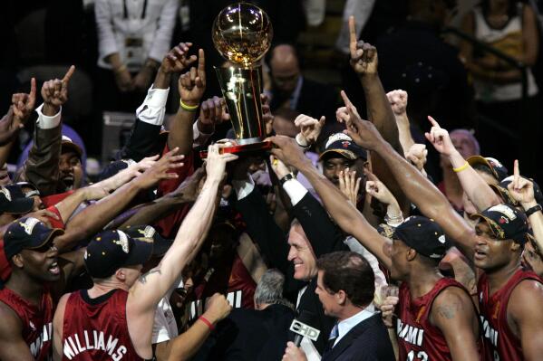 FILE - The Miami Heat reach for the Larry O'Brien Trophy after winning the NBA Championship by beating the Dallas Mavericks in Game 6 of the NBA basketball finals in Dallas, in this June 20, 2006 file photo. (AP Photo/Donna McWilliam, File)