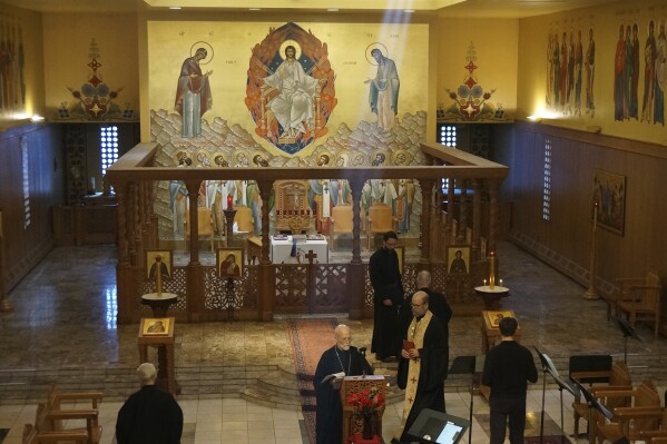 Brother Marc, center, one of the founders of the Orthodox Christian community of New Skete, and its current prior, Brother Christopher, right, holding book, finish morning prayers in the Church of Holy Wisdom, the larger of two churches of the monastery renowned for dog breeding and training programs outside Cambridge, N.Y., on Oct. 12, 2024. (AP Photo/Giovanna Dell’Orto)