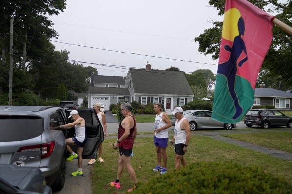 Carolyn Baker and running friends pile in to a car to be taken from her home to the start line to run in the Falmouth Road Race, Sunday, Aug. 18, 2024, in Falmouth, Mass. (AP Photo/Jeff Roberson)