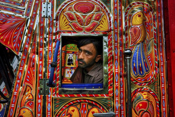 Driver Farrukh Sana looks out from the window of a newly refurbished truck at a yard for workshops in Rawalpindi, Pakistan, on Saturday, April 19, 2025. (AP Photo/Anjum Naveed)