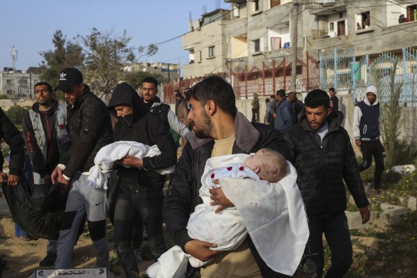 Pessoas em luto carregam os corpos de gêmeos palestinos mortos em um ataque israelense a uma casa em Rafah, sul da Faixa de Gaza, domingo, 3 de março de 2024. (AP Photo/Hatem Ali)