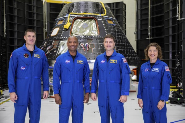 Artemis II crew members, from left, Jeremy Hansen, Victor Glover, Reid Wiseman and Christina Koch, stand together at NASA's Kennedy Space Center in Florida, in front of an Orion crew module on Tuesday, Aug. 8, 2023. The U.S.-Canadian crew inspected the capsule during a visit late Monday and Tuesday. NASA plans to send the four around the moon and back late next year. (Kim Shiflett/NASA via AP)