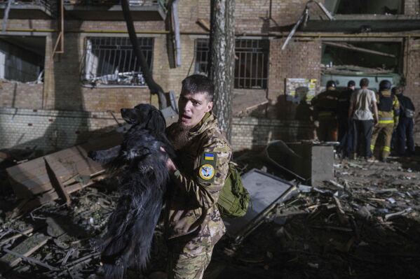 A Ukrainian serviceman carries a dog out of a house damaged by a Russian airstrike in a residential neighborhood in Kyiv, Ukraine, on Thursday, April 24, 2025. (AP Photo/Evgeniy Maloletka)