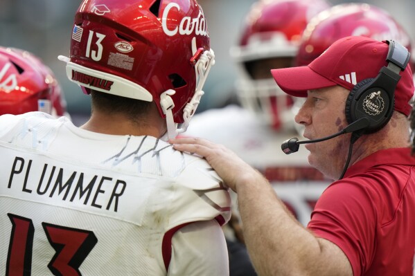 Louisville head coach Jeff Brohm, right, talks with quarterback Jack Plummer (13) during the second half of an NCAA college football game against Miami, Saturday, Nov. 18, 2023, in Miami Gardens, Fla. (AP Photo/Wilfredo Lee)