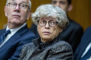 FILE- Ex-Michigan State University president Lou Anna Simon, center, listens during a preliminary hearing at the Eaton County Courthouse, June 11, 2019 in Charlotte, Mich. State prosecutors lost their bid to reinstate charges against the former MSU president who was accused of lying to investigators in 2018 when they tried to learn what she knew years earlier about sexual assault complaints involving Larry Nassar. In a 3-0 opinion Tuesday, Dec. 21, 2021, the Michigan Court of Appeals agreed that there was insufficient evidence to send her to trial. (Cory Morse/The Grand Rapids Press via AP_File)