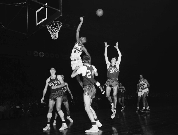 FILE - Duquesne center Jim Tucker (4) leaps for a rebound against Holy Cross players in the NIT finals at New York's Madison Square Garden, March 13, 1954. Holy Cross players, from left: Togo Palazzi (22); Joe Liebler (32); Tom Heinsohn (24) and Don Prohovich (35). Tucker was a part of a wave of Black players who helped the small Pittsburgh Catholic school become a national power in the 1940s and 1950s. (AP Photo/Marty Lederhandler, File)