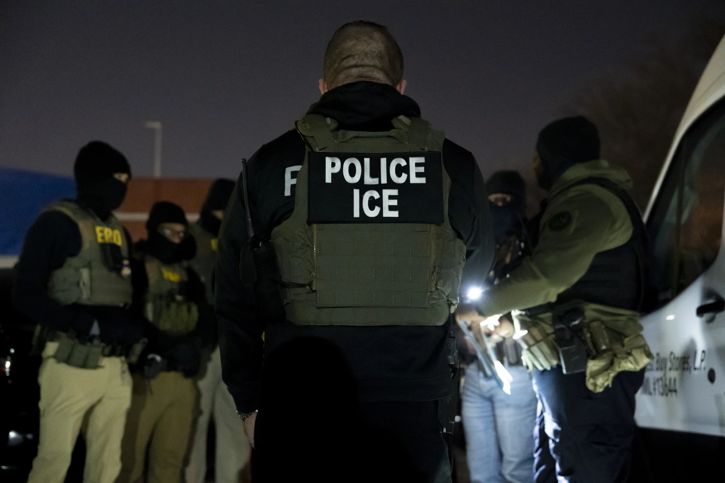 Agente de la Patrulla Fronteriza de EE.UU. camina cerca de migrantes detenidos en la frontera con México, enero de 2025