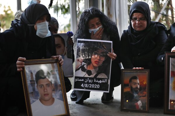 Relatives of victims of the Aug. 4 Beirut port explosion hold portraits of their loved one who killed during the explosion, during a vigil at the seaport main entrance, as they marking four months ...