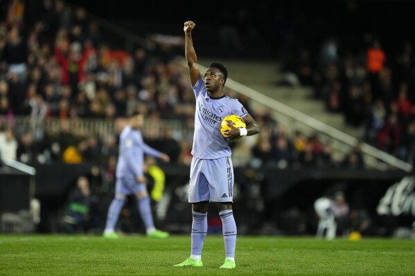 FILE - Real Madrid's Vinicius Junior celebrates after scoring his side's first goal during the La Liga soccer match between Valencia and Real Madrid at the Mestalla Stadium in Valencia, Spain, Saturday, March 2, 2024. Vinicius Junior clenched his right fist and raised it high above his head after scoring at Mestalla Stadium, posing for a moment so everyone could see him. The symbolic gesture came nearly a year after the Real Madrid forward was on that same field with tears in his eyes after being racially abused by some Valencia fans. (AP Photo/Jose Breton, File)