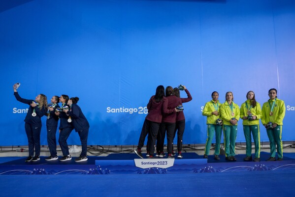 Nadadores de Estados Unidos, Canadá y Brasil, de izquierda a derecha, en el podio del relevo femenino de 4x100 metros estilo libre en los Juegos Panamericanos en Santiago, Chile, el sábado 21 de octubre de 2023.  (Foto AP/Fernando Vergara)