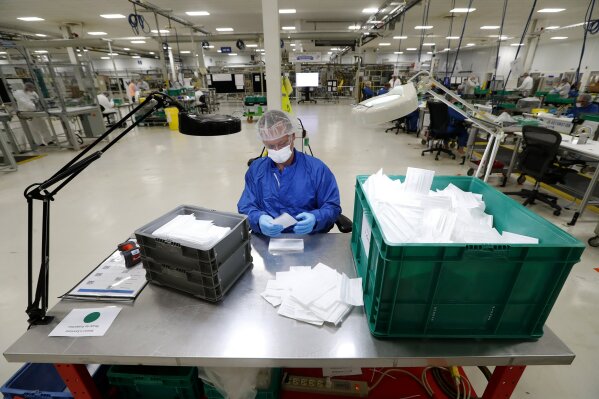 A worker checks protective masks being manufactured in Warren, Mich., Thursday, April 23, 2020. General Motors has about 400 workers at the now-closed transmission plant in suburban Detroit. All over the country, blue-collar and salaried workers have raised their hands to make medical equipment as companies repurpose factories to answer calls for help from beleaguered nurses, doctors and paramedics who are treating patients with the highly contagious new coronavirus COVID-19. (AP Photo/Paul Sancya)