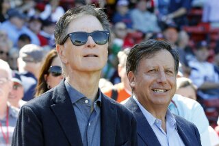 FILE - In this Sept. 27, 2015, file photo, Boston Red Sox owners John Henry, left, and Tom Werner look on before a baseball game between the Red Sox and the Baltimore Orioles in Boston. Henry and Werner intend to slash payroll to get under the luxury tax threshold next season, saying they fired Dave Dombrowski because of differing opinions on how to build for the future. The pair made their first public comments Friday, Sept. 27, 2019, since parting with Dombrowski, the president of baseball operations, on Sept. 8. (AP Photo/Michael Dwyer, File)
