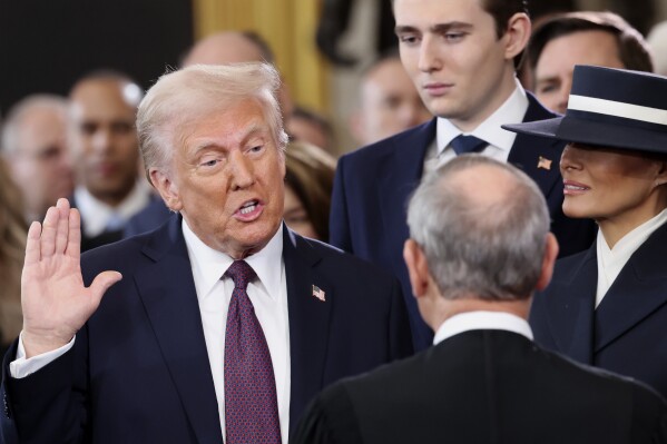 President-elect Donald Trump, from left, takes the oath of office as son Barron Trump and wife Melania Trump watch during the 60th Presidential Inauguration in the Rotunda of the U.S. Capitol in Washington, Monday, Jan. 20, 2025. (Kevin Lamarque/Pool Photo via AP)