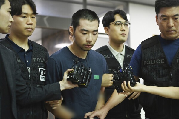 Choi Won-jong, center, speaks as he is transferred to the prosecution at a police station in Seongnam, South Korea on Aug. 10 2023. A South Korean judge convicted a man of murder Thursday for an unprovoked car-and-stabbing rampage that killed two people and injured 12 others in a city near Seoul last year. (Kim Jong-taek/Newsis via AP)
