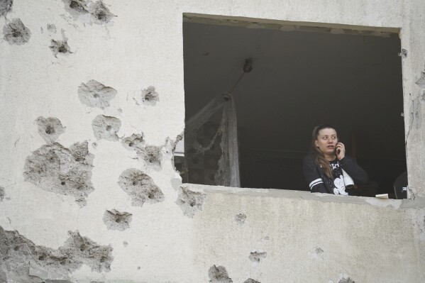 A woman looks though the window of her damaged apartment following a Russian strike in Kharkiv, Ukraine, Friday April 18, 2025. (AP Photo/Andrii Marienko)