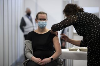 An employee of the Municipal Health Service GGD administers a Pfizer-BioNTech COVID-19 vaccine to a health care worker at a coronavirus vaccination facility in Houten, central Netherlands, Friday, Jan. 8, 2021. (AP Photo/Peter Dejong)