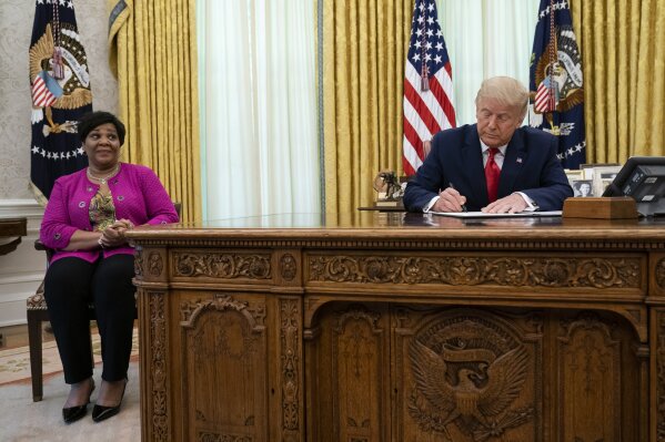President Donald Trump signs a full pardon for Alice Johnson in the Oval Office of the White House, Friday, Aug. 28, 2020, in Washington. (AP Photo/Evan Vucci)
