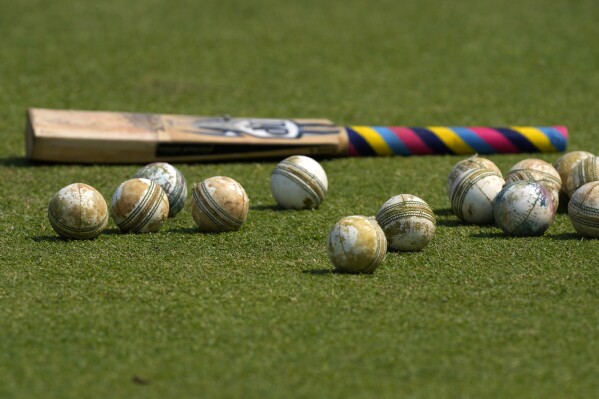 FILE -Cricket balls and a bat is seen on the ground before the start of ICC Men's Cricket World Cup match between New Zealand and South Africa in Pune, India, Wednesday, Nov.1, 2023. Transgender women will not be allowed to compete in international women’s cricket. The International Cricket Council (ICC) said the “new gender eligibility regulation” had been imposed to protect the integrity of women’s cricket and was also made on safety grounds. (AP Photo/Manish Swarup, File)