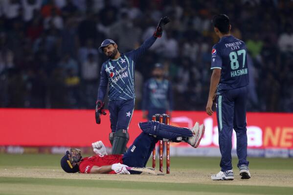 Pakistan's Mohammad Rizwan, center back, and Mohammad Hasnain talk to England's Dawid Malan, center bottom, who loses his balance when playing a shot during the seventh twenty20 cricket match between Pakistan and England, in Lahore, Pakistan, Sunday, Oct. 2, 2022. (AP Photo/K.M. Chaudary)