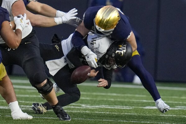 Wake Forest quarterback Michael Kern (15) fumbles the ball as he's tackled but Notre Dame linebacker JD Bertrand (27) during the second half of an NCAA college football game in South Bend, Ind., Saturday, Nov. 18, 2023. (AP Photo/Michael Conroy)