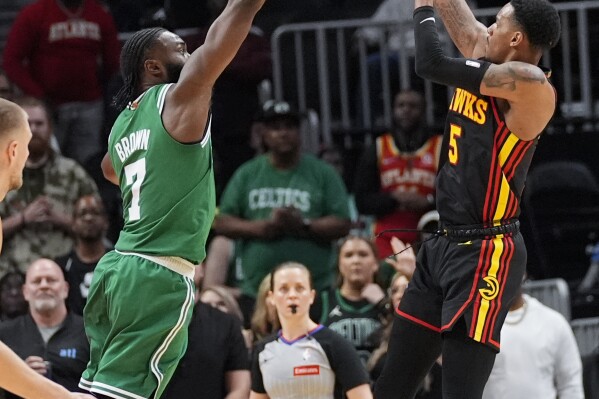 Atlanta Hawks guard Dejounte Murray (5) shoots as Boston Celtics guard Jaylen Brown (7) defends during overtime in an NBA basketball game Thursday, March 28, 2024, in Atlanta. (AP Photo/John Bazemore)