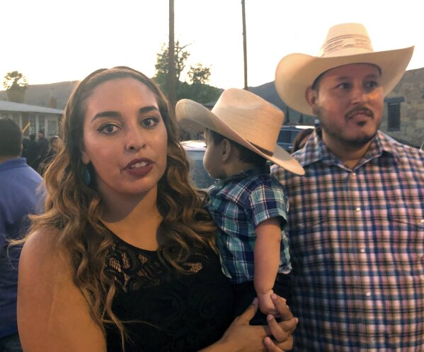 Isabel Regalado, 27, left, her son, Preston Regalado-Soliz, 10-months, and her husband, Esteban Soliz, 38, right, stand in line with thousands of others on Friday, Aug. 16, 2019, to pay respects to Margie Reckard, 63, who was killed by a gunman who opened fire at a Walmart in El Paso, Tex., earlier this month. Thousand of strangers from El Paso and around the country came this weekend to honor Reckard. Her long-time companion, Antonio Basco, says he felt so alone planning her funeral, that he invited the world to join him in remembering his companion of 22 years. (AP Photo/Russell Contreras)