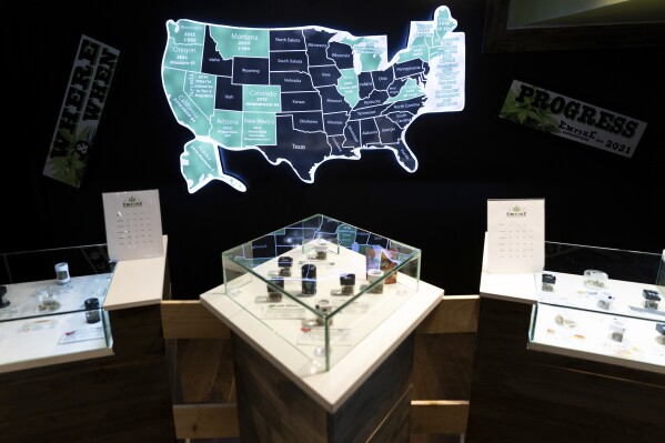 FILE - A map of cannabis legalization in the U.S. glows behind flower displays at the Empire Cannabis Club, Nov. 16, 2022, in New York. An advisory board approved on Tuesday, Feb. 13, 2024 a list of proposed rules and regulations that would govern the recreational use of cannabis in the U.S. Virgin Islands. (APPhoto/Julia Nikhinson, File)