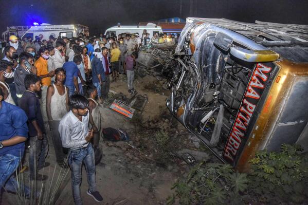 Onlookers gather near the wreckage after a bus carrying migrant workers after the lifting of coronavirus restrictions hit a delivery van on a highway near Kanpur, Uttar Pradesh state, India, Tuesday, June 8, 2021. More than a dozen people were killed. (AP Photo)