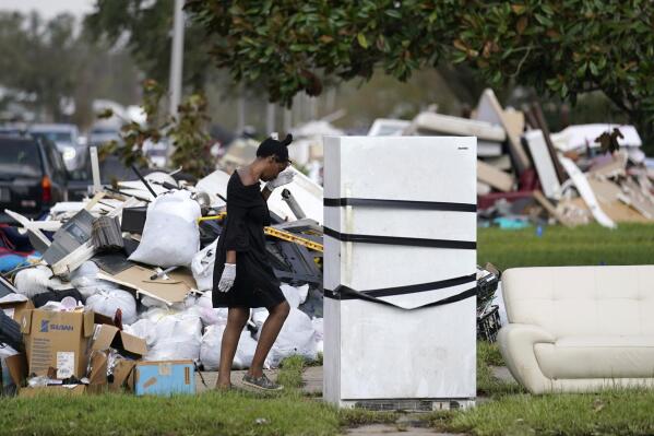 Lori Butler wipes her brow as she moves debris she is gutting from her home that was flooded, in the aftermath of Hurricane Ida in LaPlace, La., Tuesday, Sept. 7, 2021. (AP Photo/Gerald Herbert)