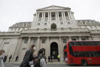 FILE - In this Wednesday, March 11, 2020 file photo, pedestrians wearing face masks pass the Bank of England in London. The Bank of England said Thursday May 6, 2021, it will keep interest rates on hold and has grown more optimistic about the economic recovery in the U.K. as a result of the rapid rollout of coronavirus vaccines. (AP Photo/Matt Dunham, File)