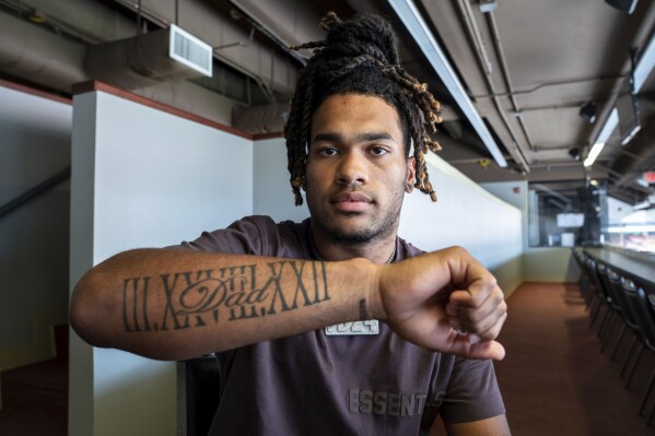 In this undated photo provided by the University of Texas, Texas running back Jonathon Brooks displays a tattoo to honor the memory of his late father, James “Skip” Brooks, in Austin, Texas. The Roman numerals represent March 28, 2022, when his father died. Jonathon Brooks taps the tattoo every time he scores a touchdown. (Ashleigh Young/University of Texas via AP)