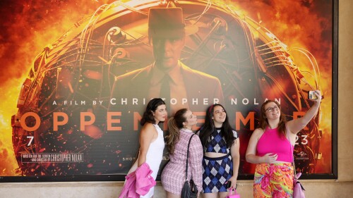 From left, Gabrielle Roitman, Kayla Seffing, Maddy Hiller and Casey Myer take a selfie in front of an "Oppenheimer" movie poster before they attended an advance screening of "Barbie," Thursday, July 20, 2023, at AMC The Grove 14 theaters in Los Angeles. (AP Photo/Chris Pizzello)