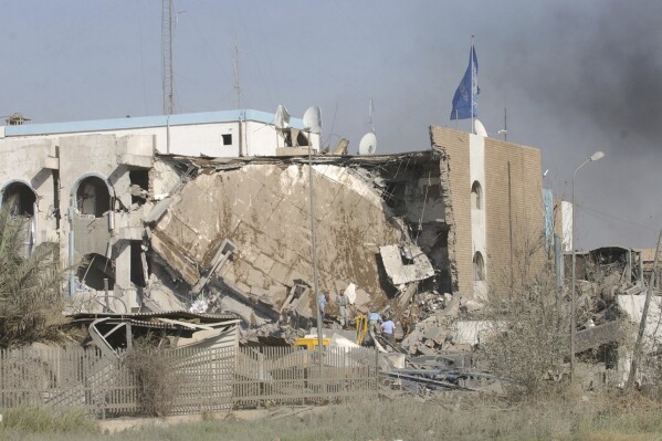 FILE - Unidentified people inspect the rubble of the al-Canal Hotel which houses the United Nations headquarters, after an explosion Tuesday, Aug. 19, 2003, in Baghdad, Iraq. Iraqi and United Nations officials on Saturday marked the 20th anniversary of a deadly attack on the U.N. headquarters in Baghdad. (AP Photo/Wally Santana, File)